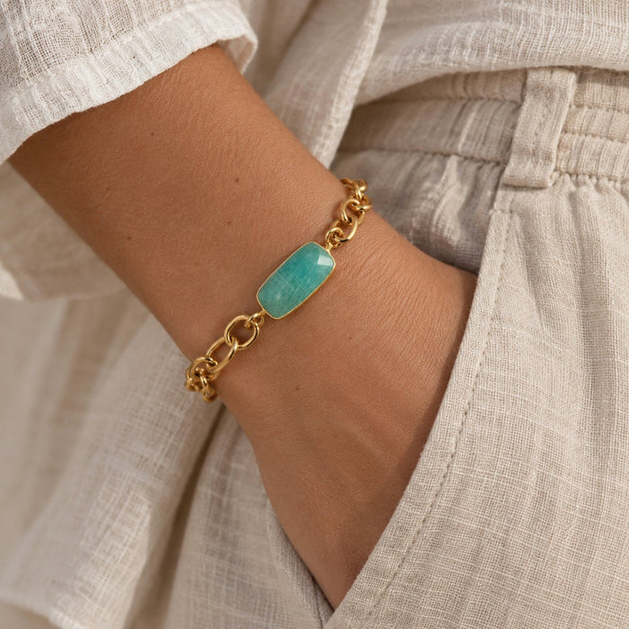 A gold chain bracelet with a rectangular amazonite stone centerpiece, shown worn on a person's wrist.